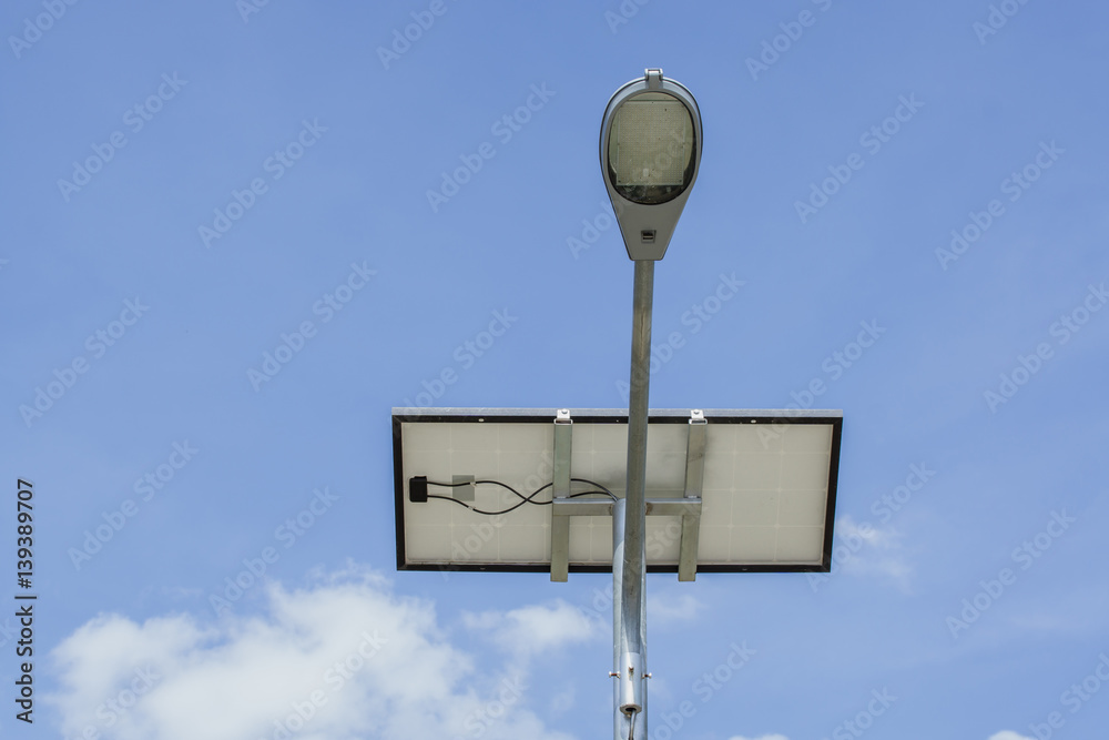 Solar powered street light on blue sky background with clouds.