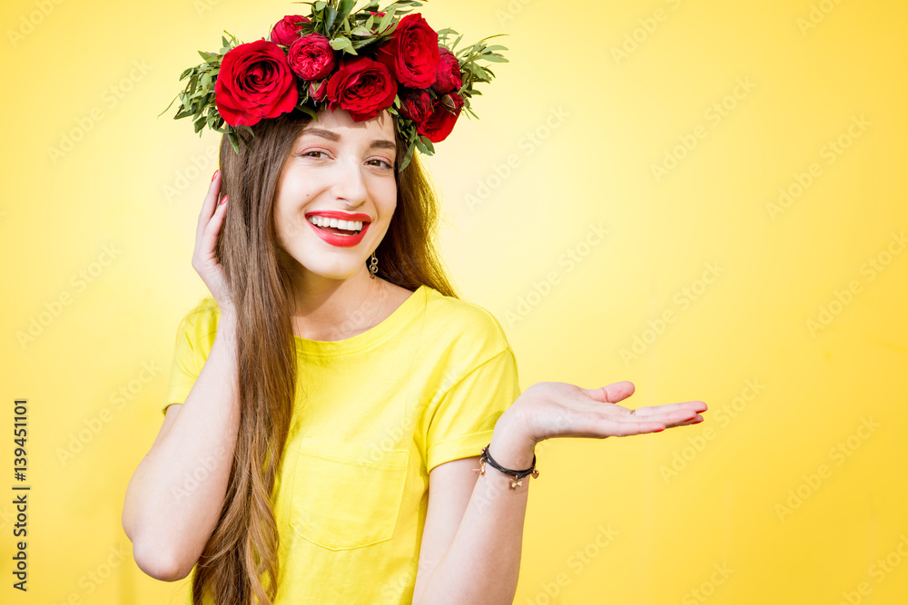 Colorful portrait of a beautiful woman in yellow t-shirt with wreath made of red roses on the yellow