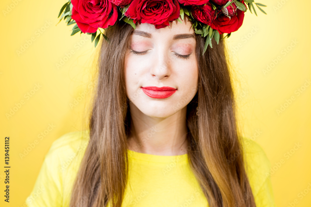 Close-up portrait of a beautiful woman with wreath made of red roses on the yellow background