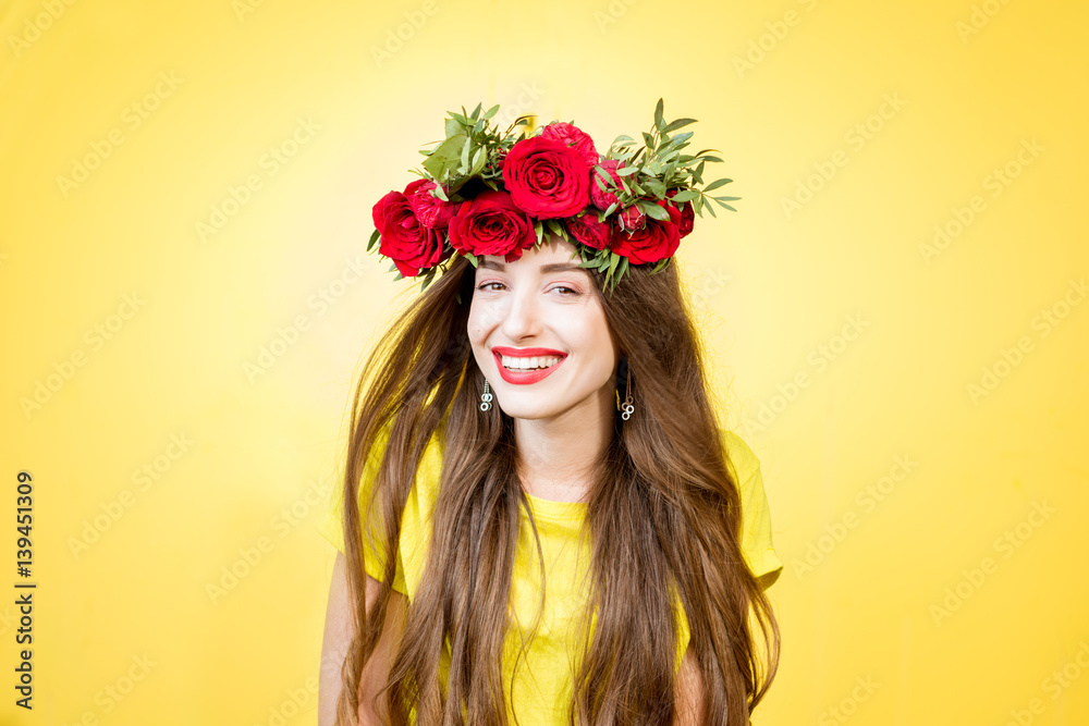 Colorful portrait of a beautiful woman in yellow t-shirt with wreath made of red roses on the yellow