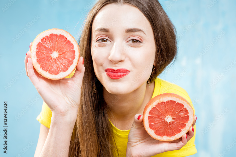 Colorful portrait of a beautiful woman grapefruit slices on the yellow background