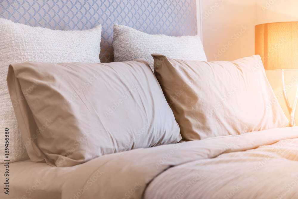 Bed maid-up with clean white pillows and bed sheets in beauty room. Close-up. Lens flair in sunlight