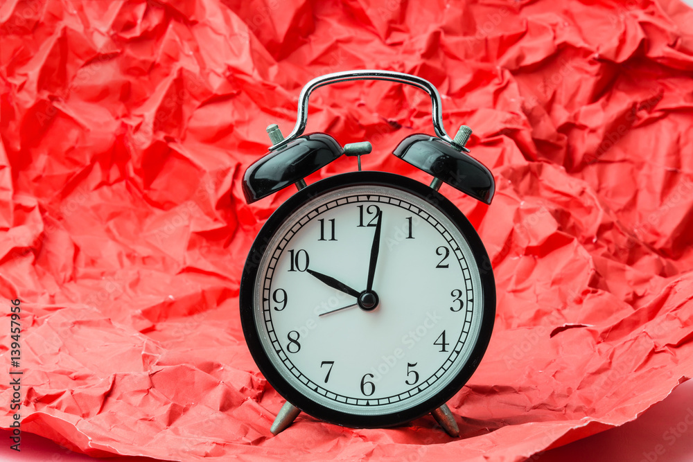 black alrm clock on trash crumpled red paper times concept