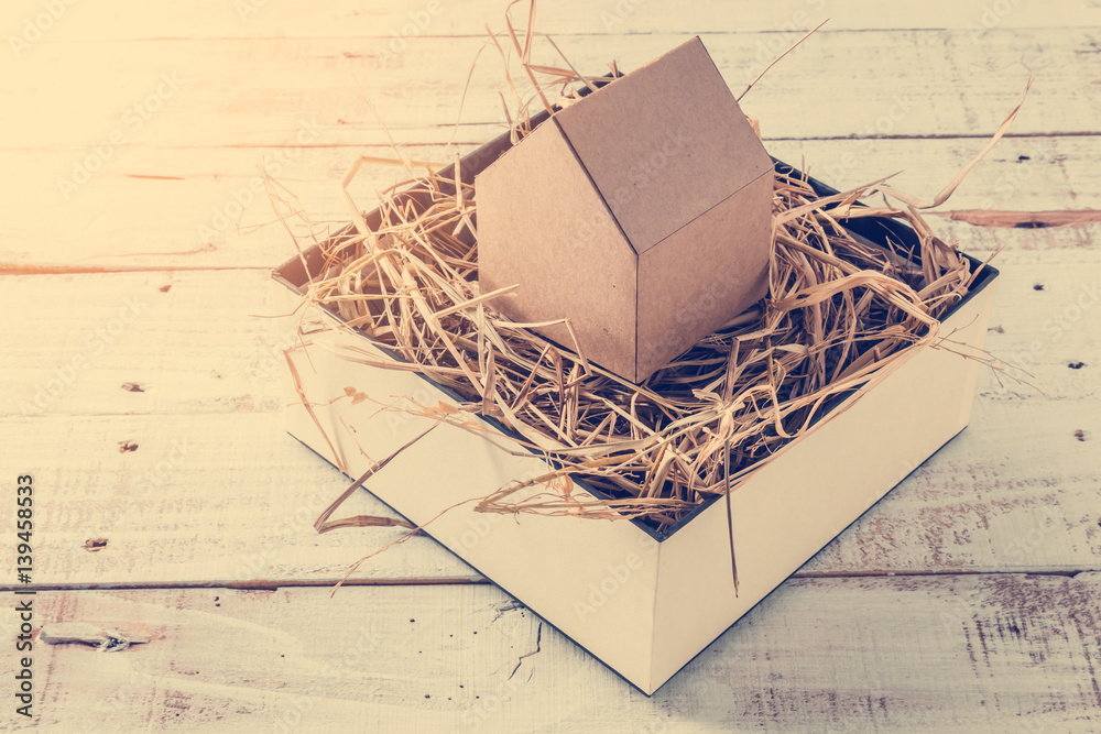 house model cardboard in a box with hay and free copyspace house concept