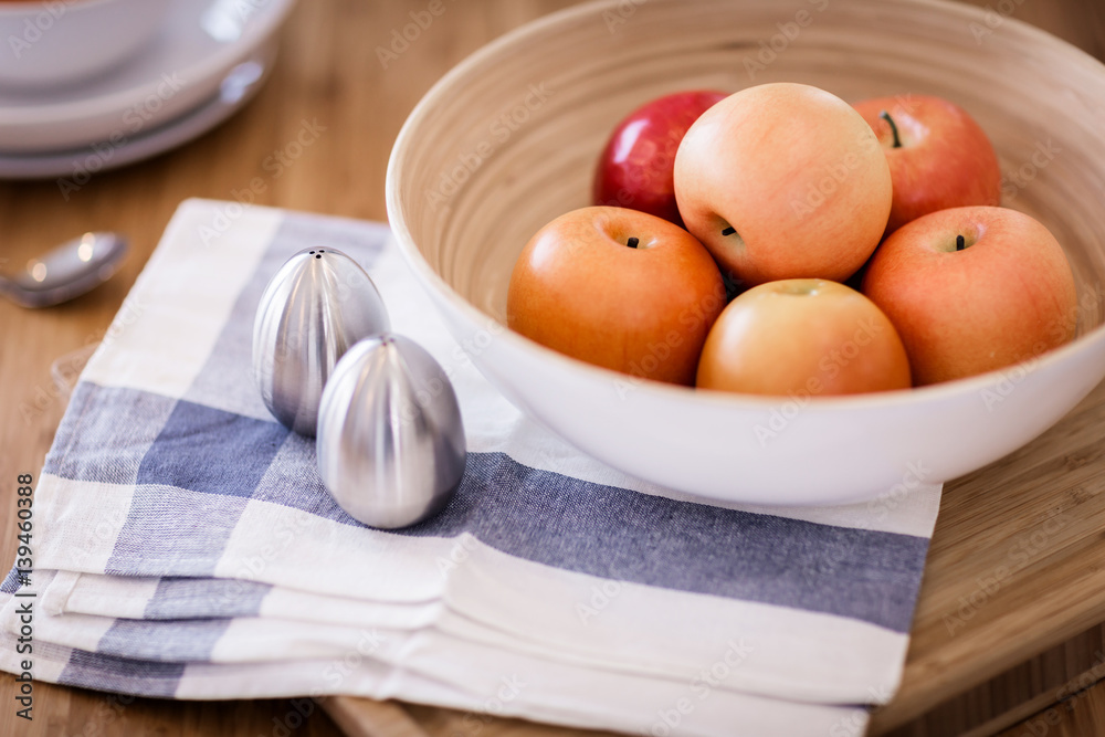 red apple in wooden bowl on color checker fabric with moring light on wooden table