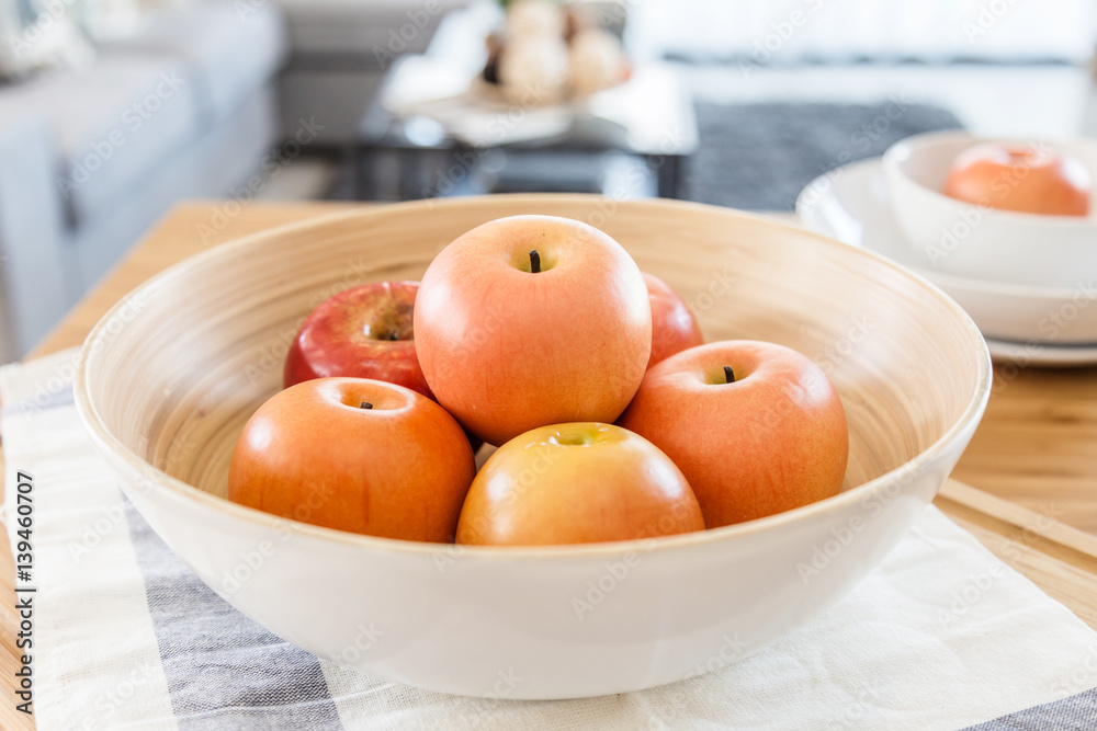 red apple in wooden bowl on color checker fabric with moring light on wooden table