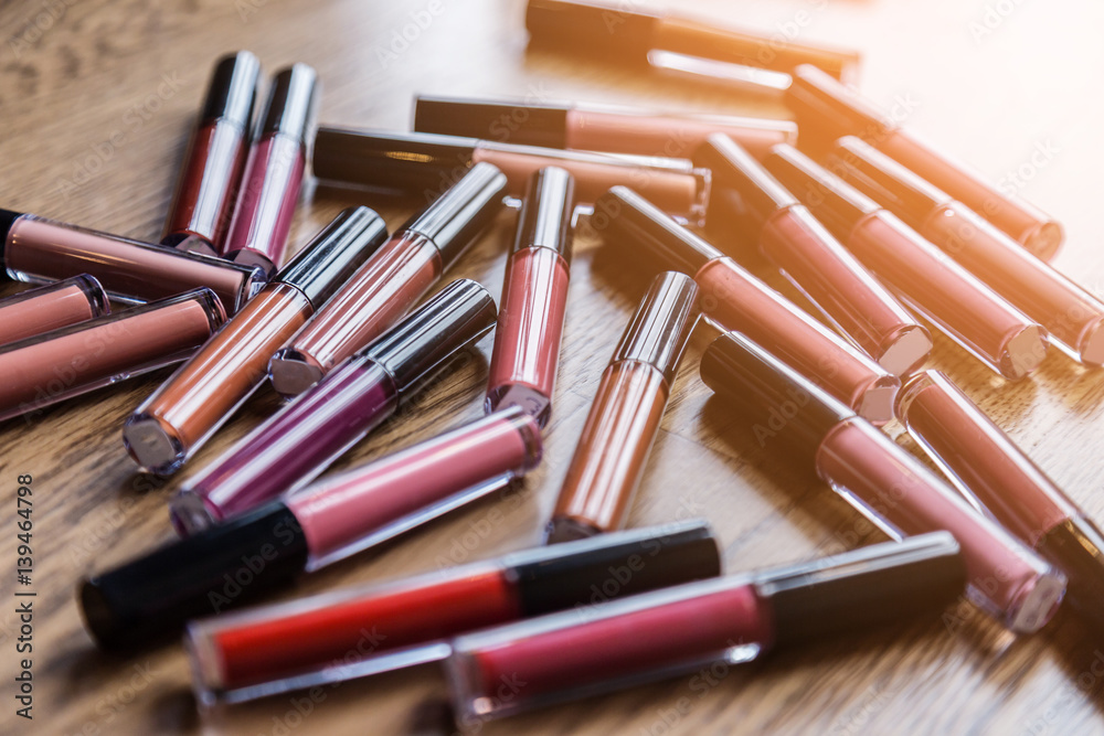 heap of bottle liquip lipstick on wooden table with free copyspace