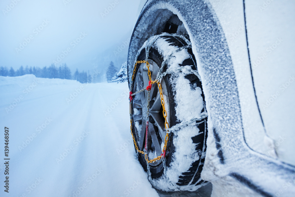 Car with snow chains for tire on snowcapped road