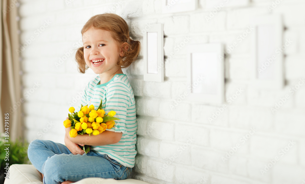 happy laughing  child girl with  yellow tulips at home