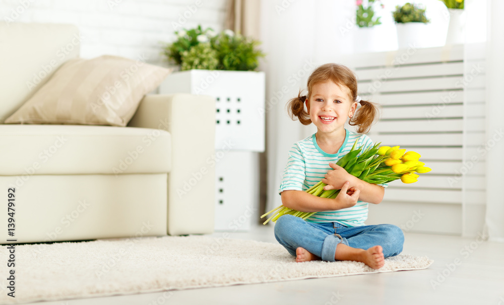 happy laughing  child girl with  yellow tulips at home