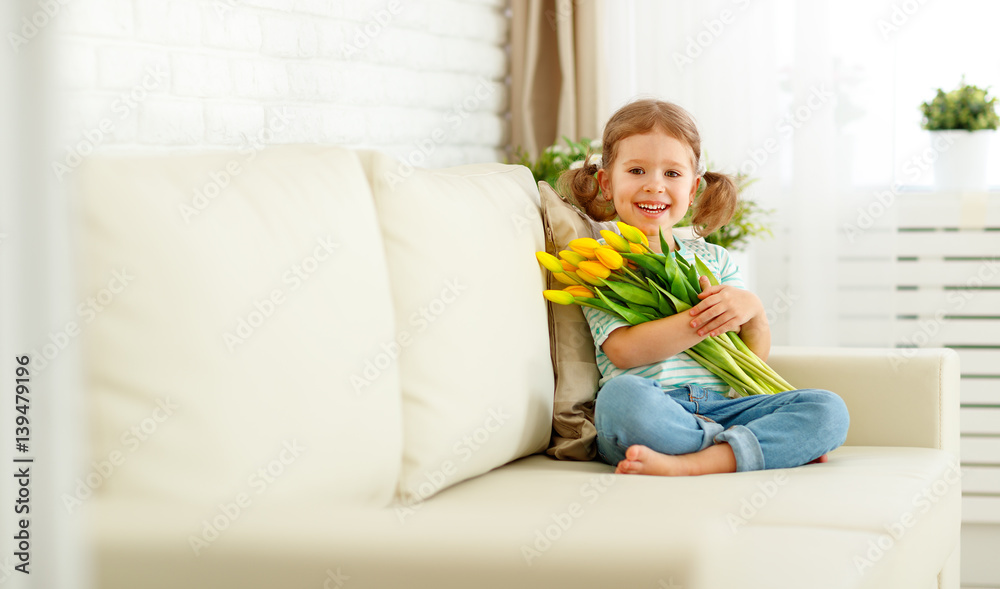 happy laughing  child girl with  yellow tulips at home