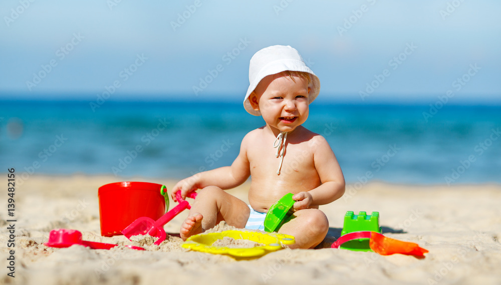 baby boy playing with toys and sand on beach