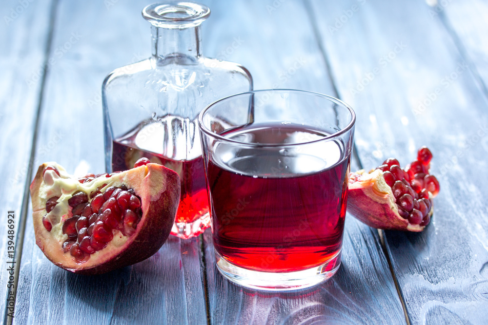 bottle of pomegranate juice with slices on wooden table