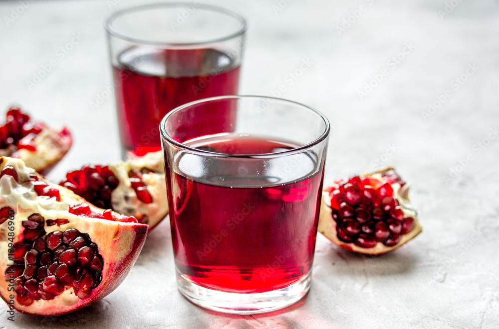 glass of pomegranate juice with fresh slices on stone background