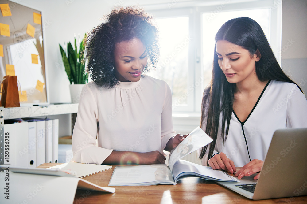 Two young businesswomen working on a report