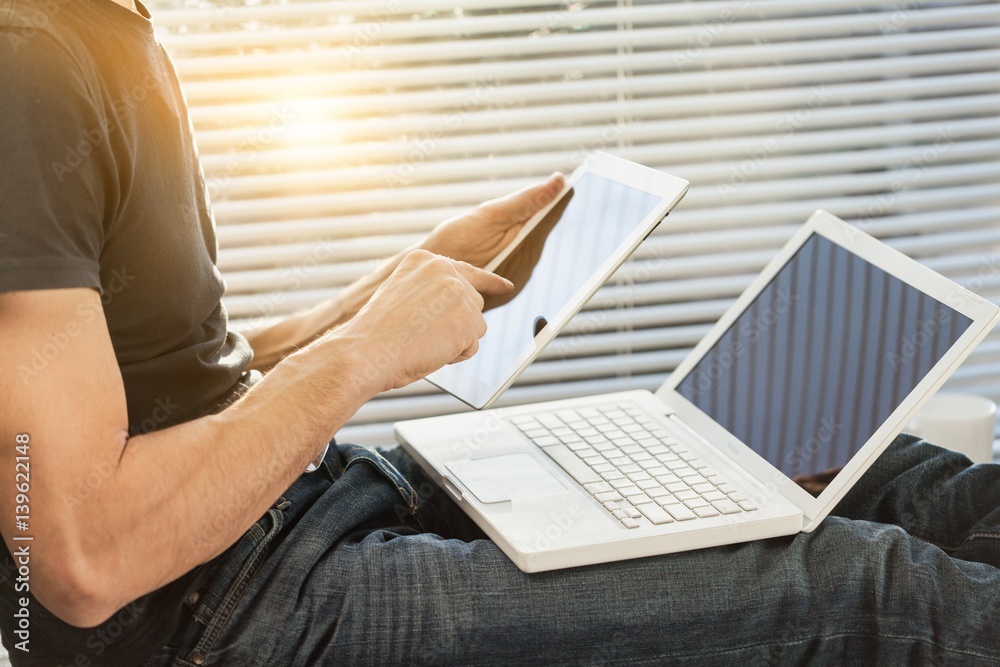 Business man works on digital tablet and laptop.