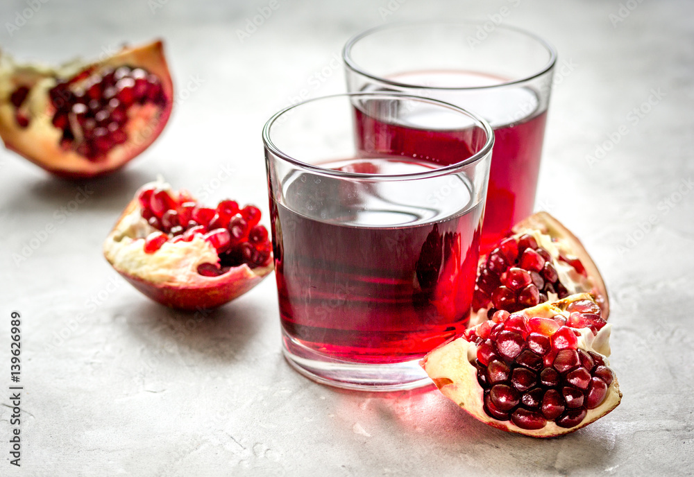 ripe pomergranate and glass of juice on table background