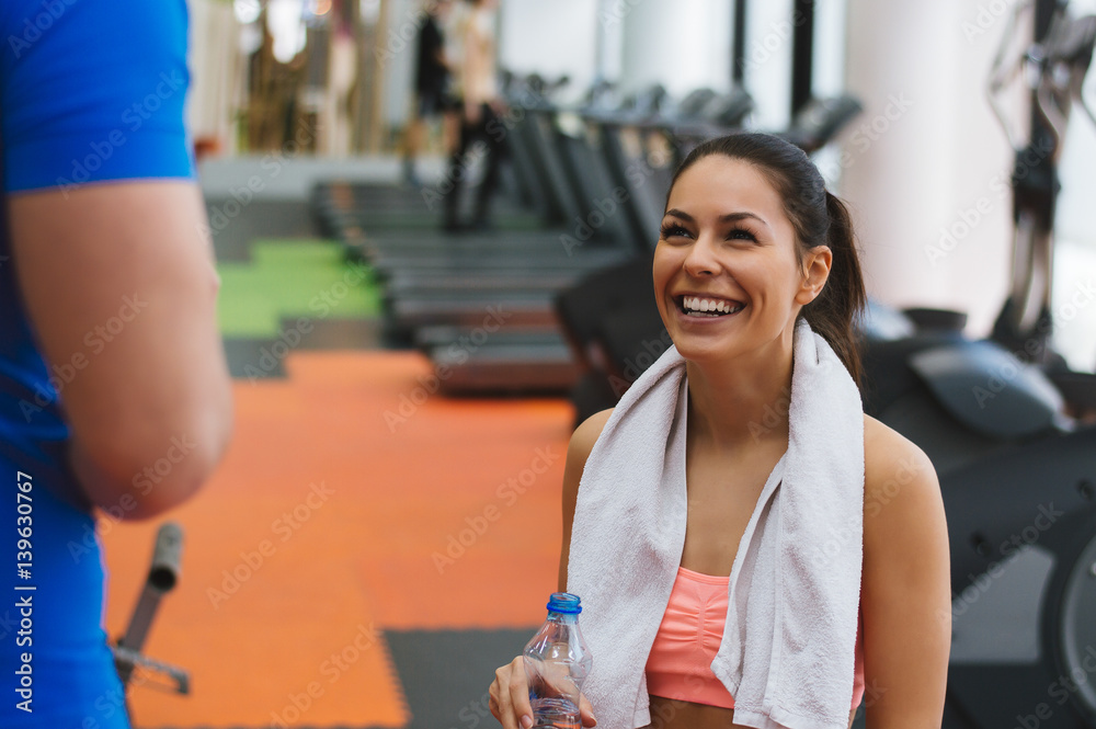 Beautiful young woman smiling at gym while taking a break