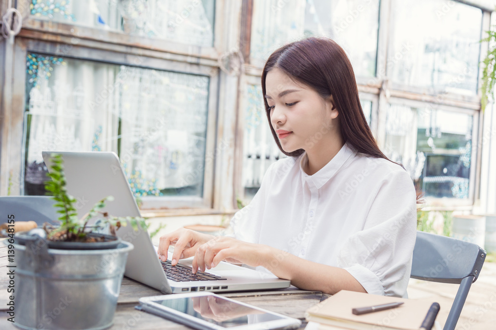 young casual asian woman using technology on her laptop computer outdoor in her garden