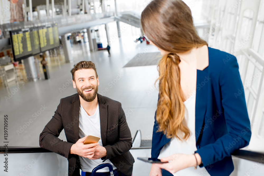 Business couple getting up with baggage on the escalators at the airport. Business travel concept