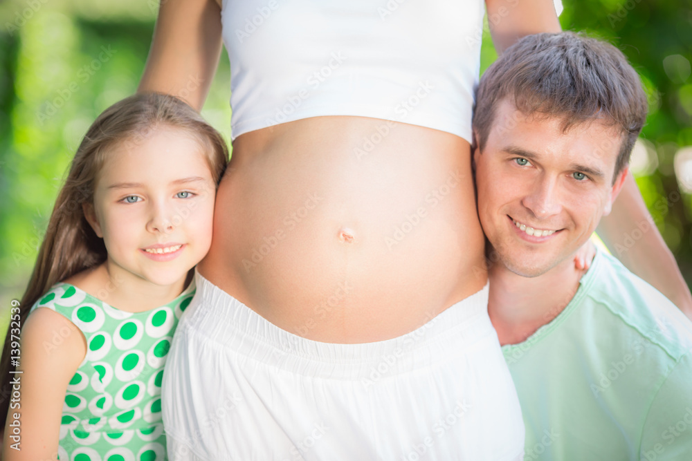 Happy family holding belly of pregnant woman