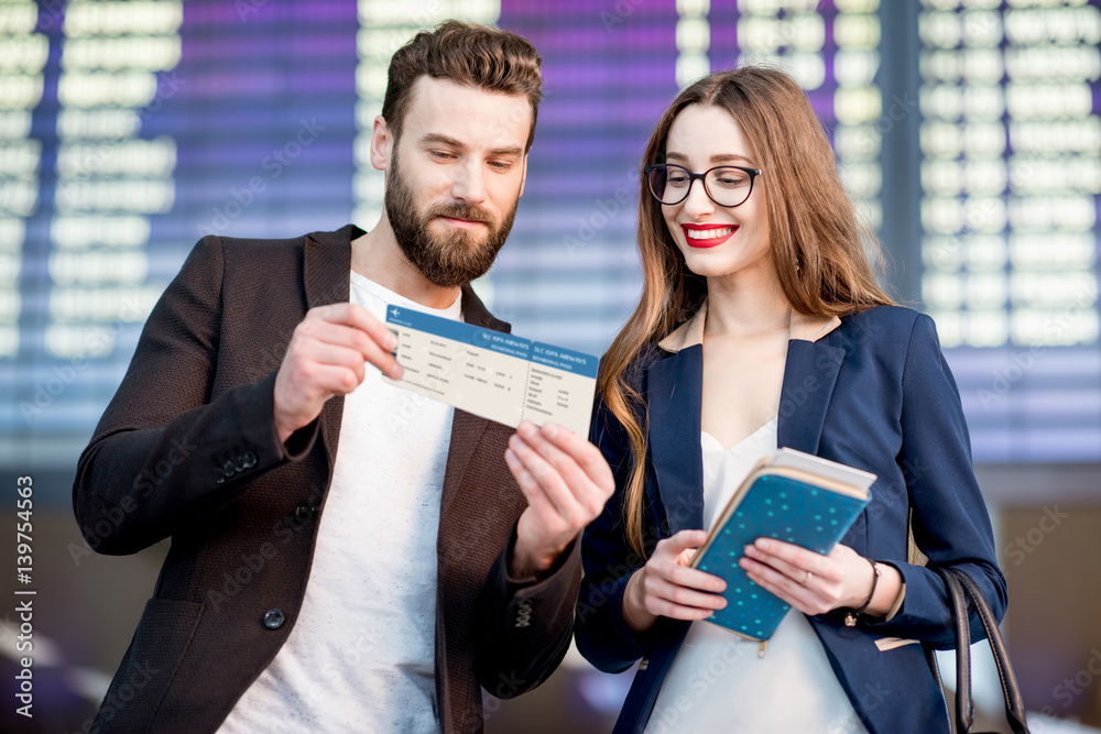 Business couple looking at the boarding pass checking the departure time in front of the airplane sc