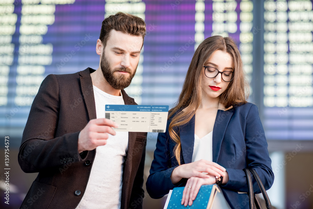 Stressed business couple looking at the boarding pass checking the departure time in front of the ai