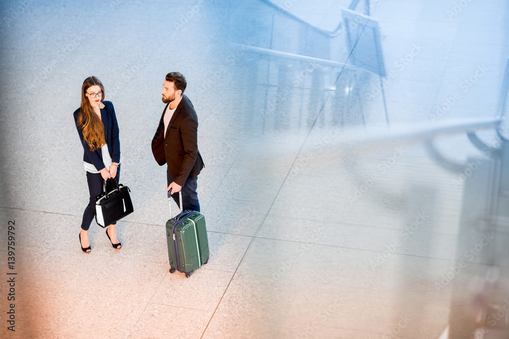 Business couple standing together with baggage at the airport. Top view with reflection