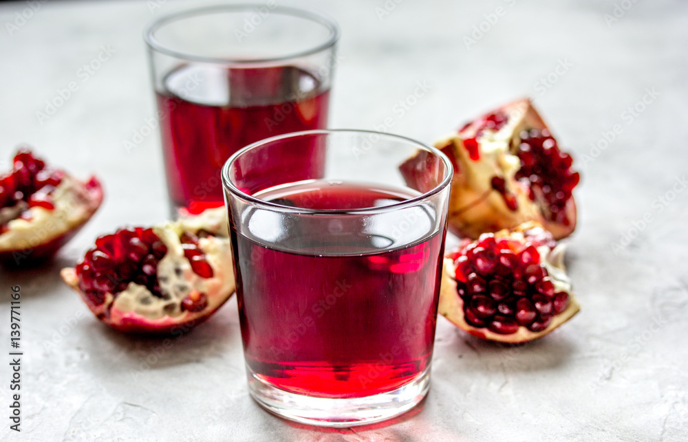 glass of pomegranate juice with fresh slices on stone background