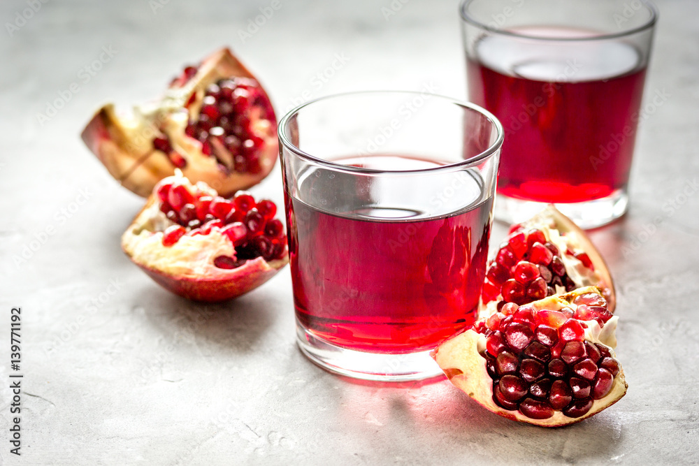 ripe pomergranate and glass of juice on table background