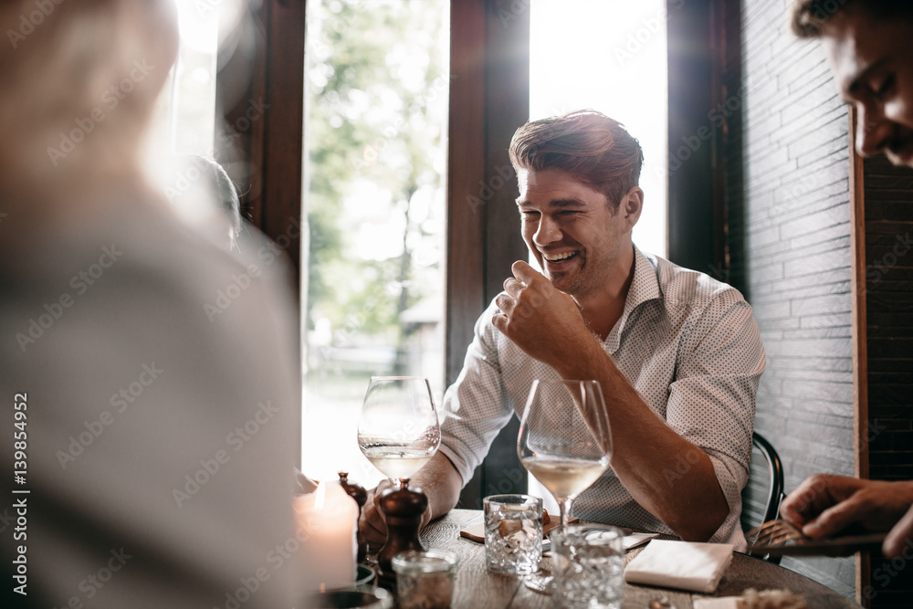 Young man smiling with friends at restaurant