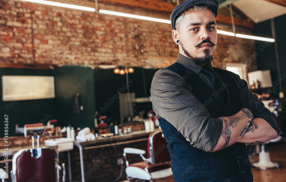 Serious young man standing at barber shop