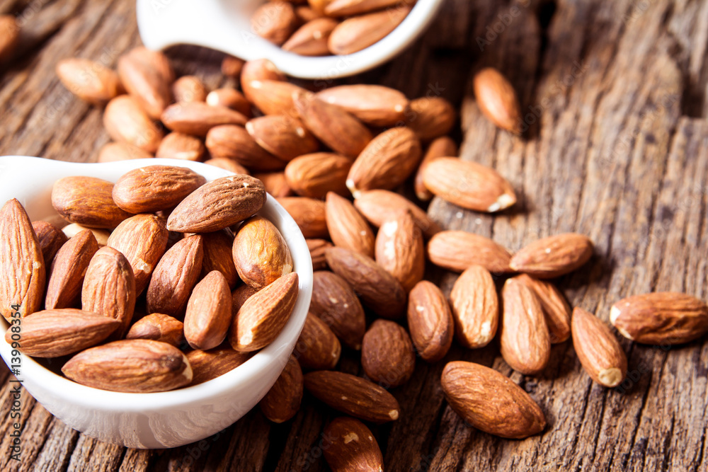 close up Peeled almonds nut  in small white cup on wooden  background