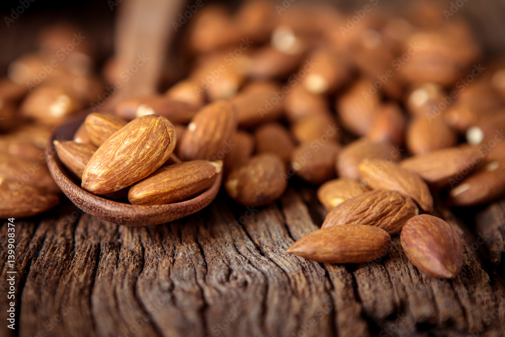 close up Peeled almonds nut in spoon on wooden  background