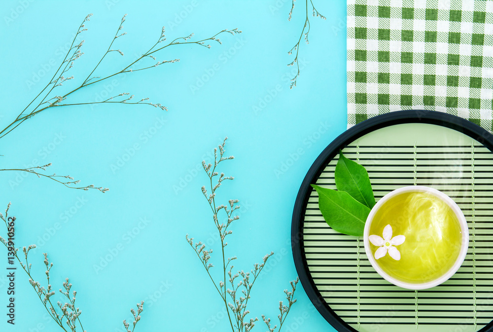 Top view shot of a hot cup of tea with green leaf decoration  with green napkin on blue background ,