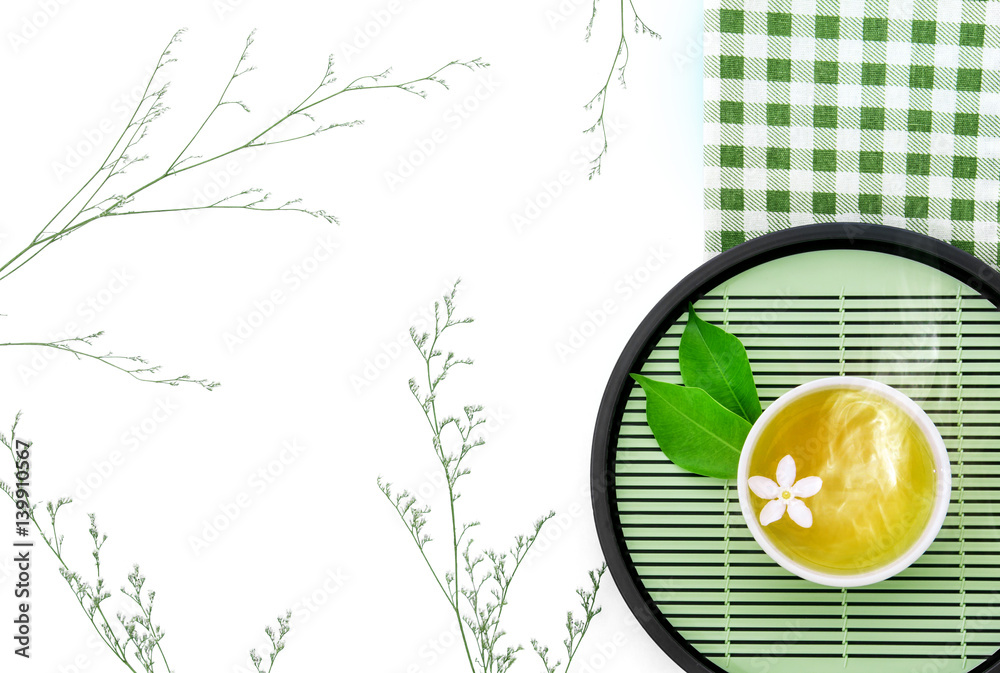 Top view shot of a hot cup of tea with green leaf decoration  with green napkin on white background 