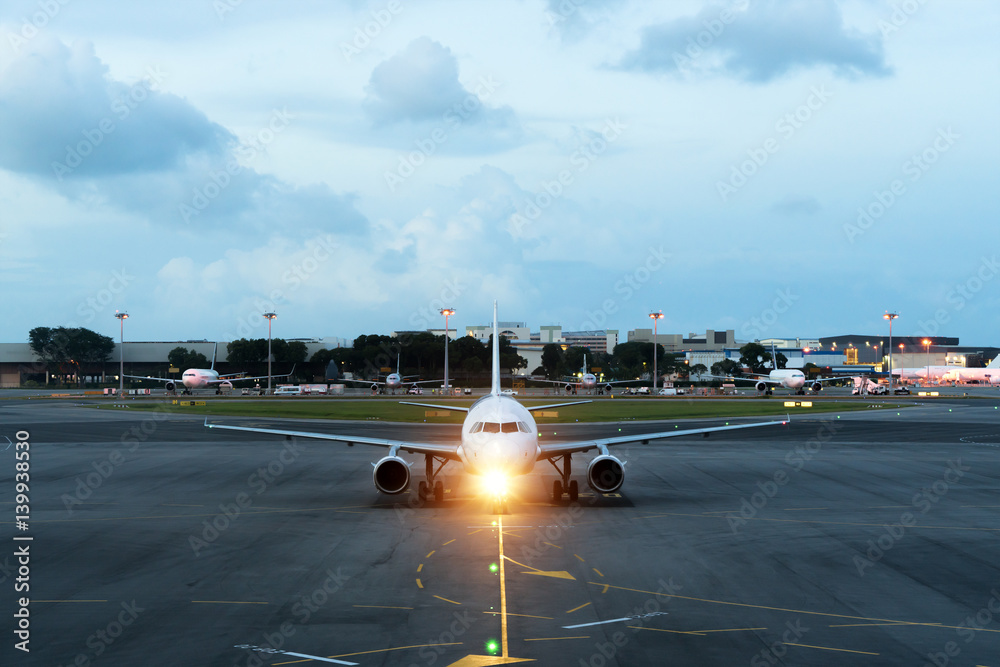 White passenger plane takes off from the airport runway. Aircraft moves against the backdrop of nigh