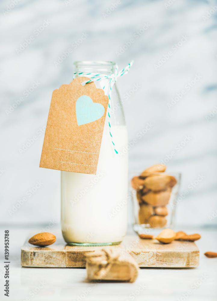 Fresh vegan dairy-free almond milk in glass bottle with craft paper label with copy space, grey marb