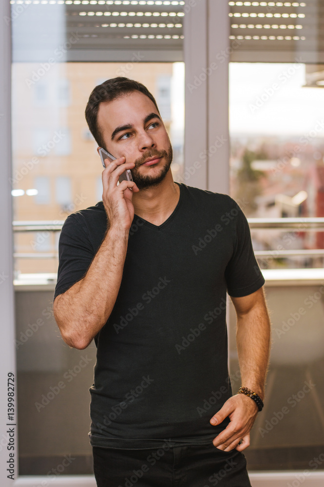 Portrait of young man talking on telephone and looking aside