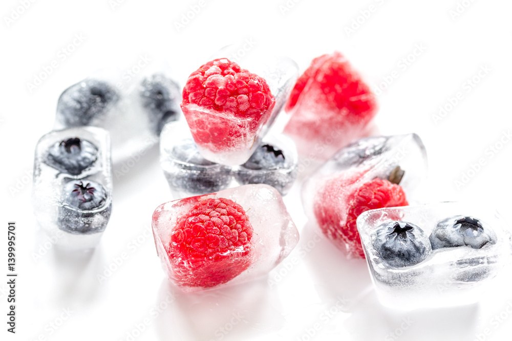 frozen blueberry and raspberry in ice cubes on white background