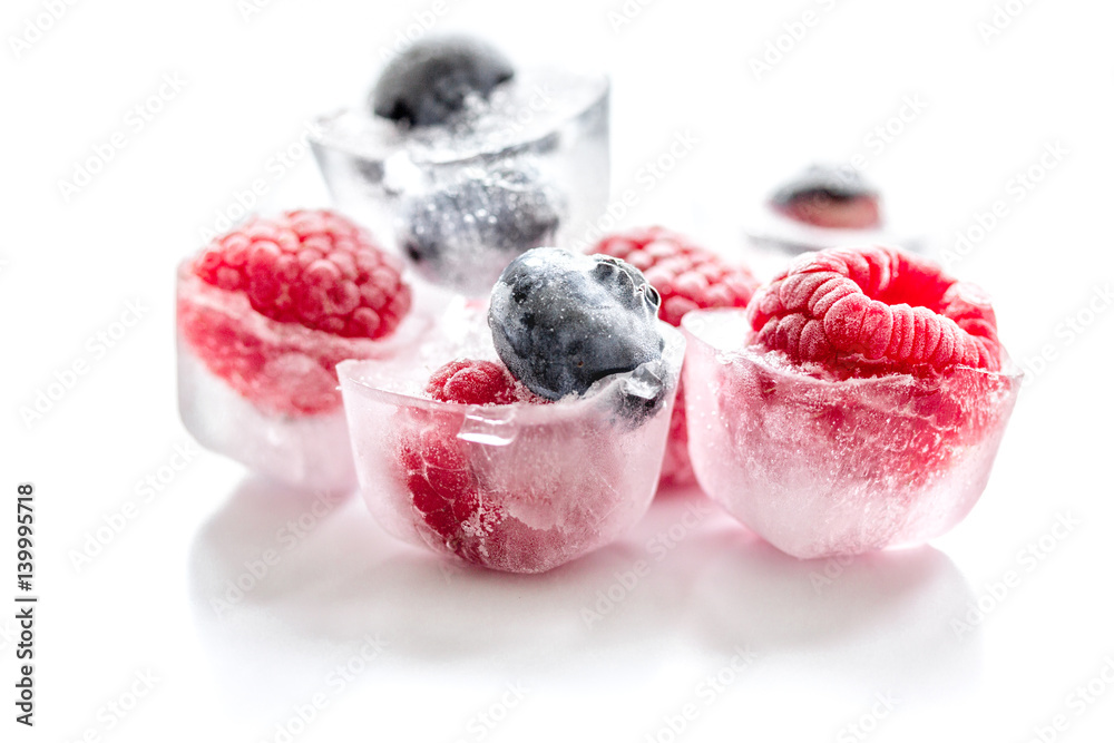 ice cubes with raspberry and blueberry on white background