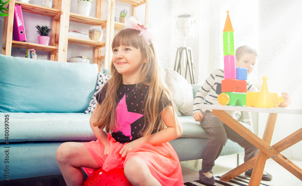 Siblings playing with blocks and fitness ball at home