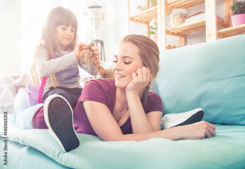 Daughter braiding mothers long hair, happy loving family