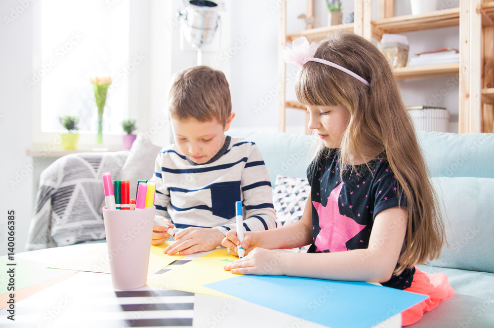 Brother and sister drawing with colorful pencils at home