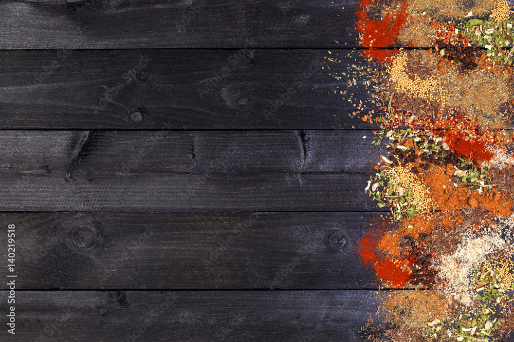 Herbs and spices over black wooden background. Top view with copy space