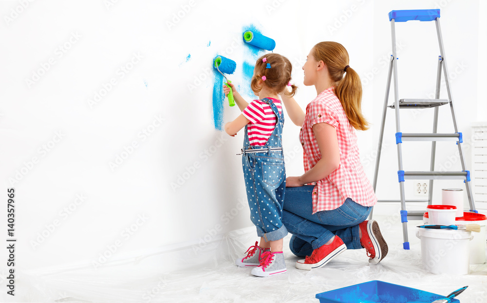 Repair in apartment. Happy family mother and child daughter paints wall .