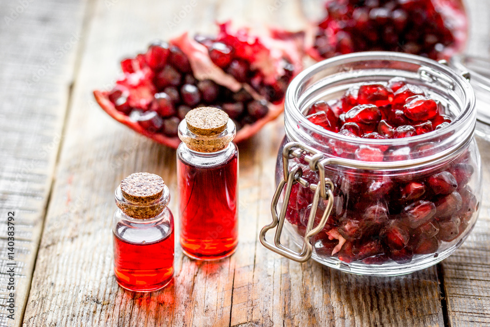 sliced pomegranate and extract in glass on wooden background