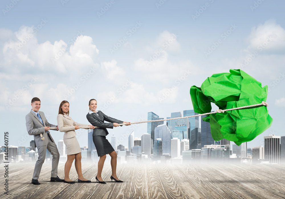 Young business people outdoors and huge paper ball as symbol of creativity