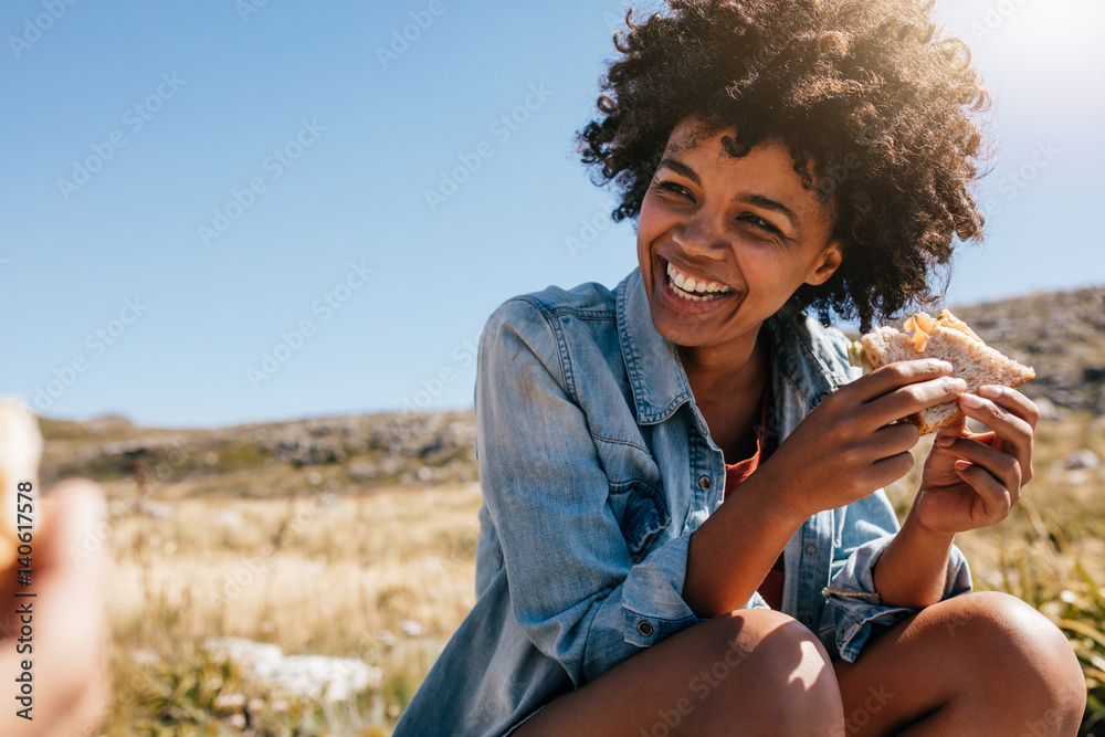 Happy young woman taking break during country hike.