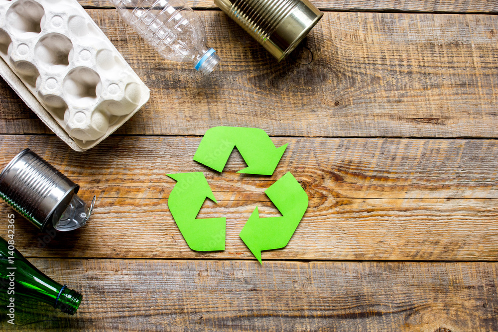 waste recycling symbol with garbage on wooden background top view mock-up